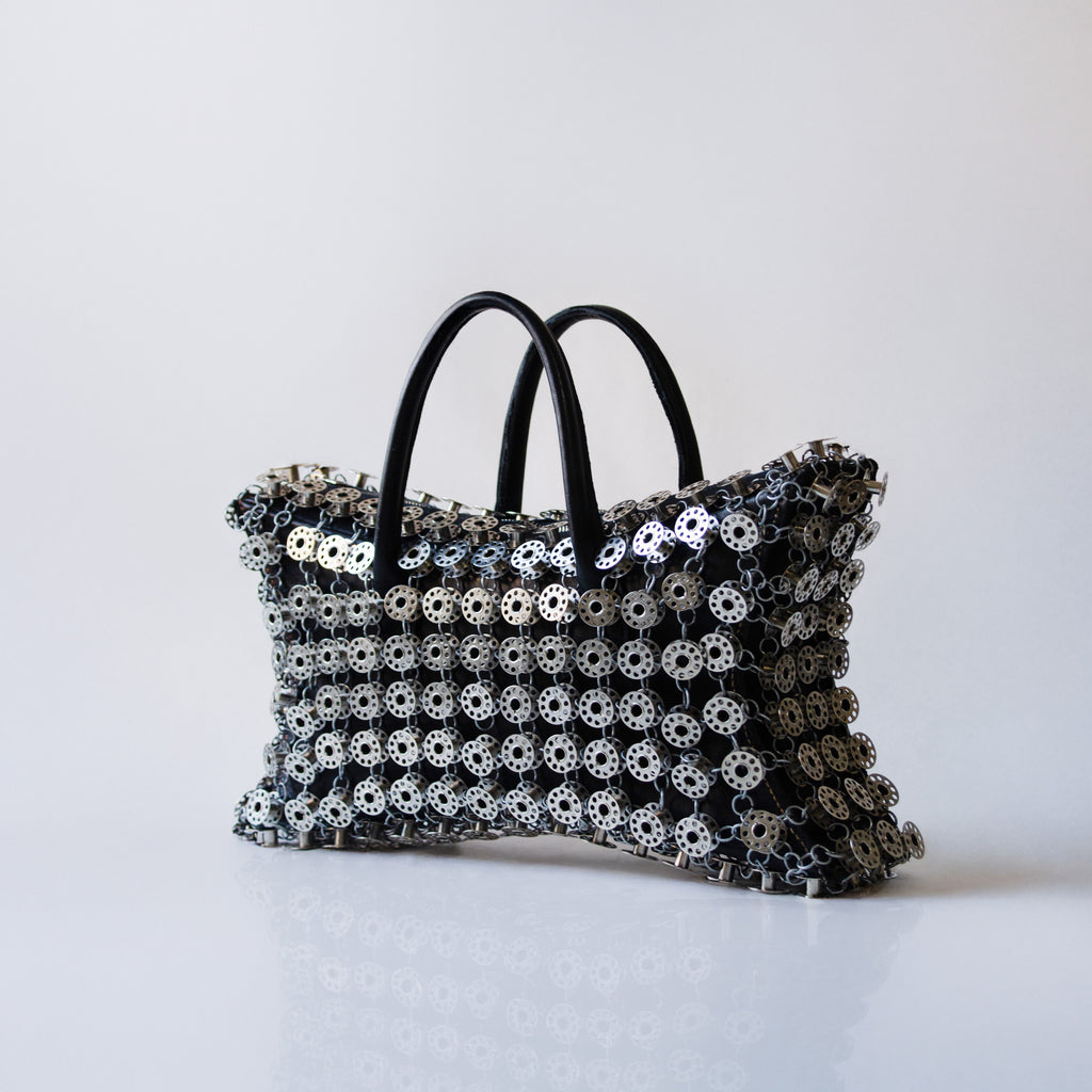 black leather star shaped handbag layered with metal bobbins on light gray background 