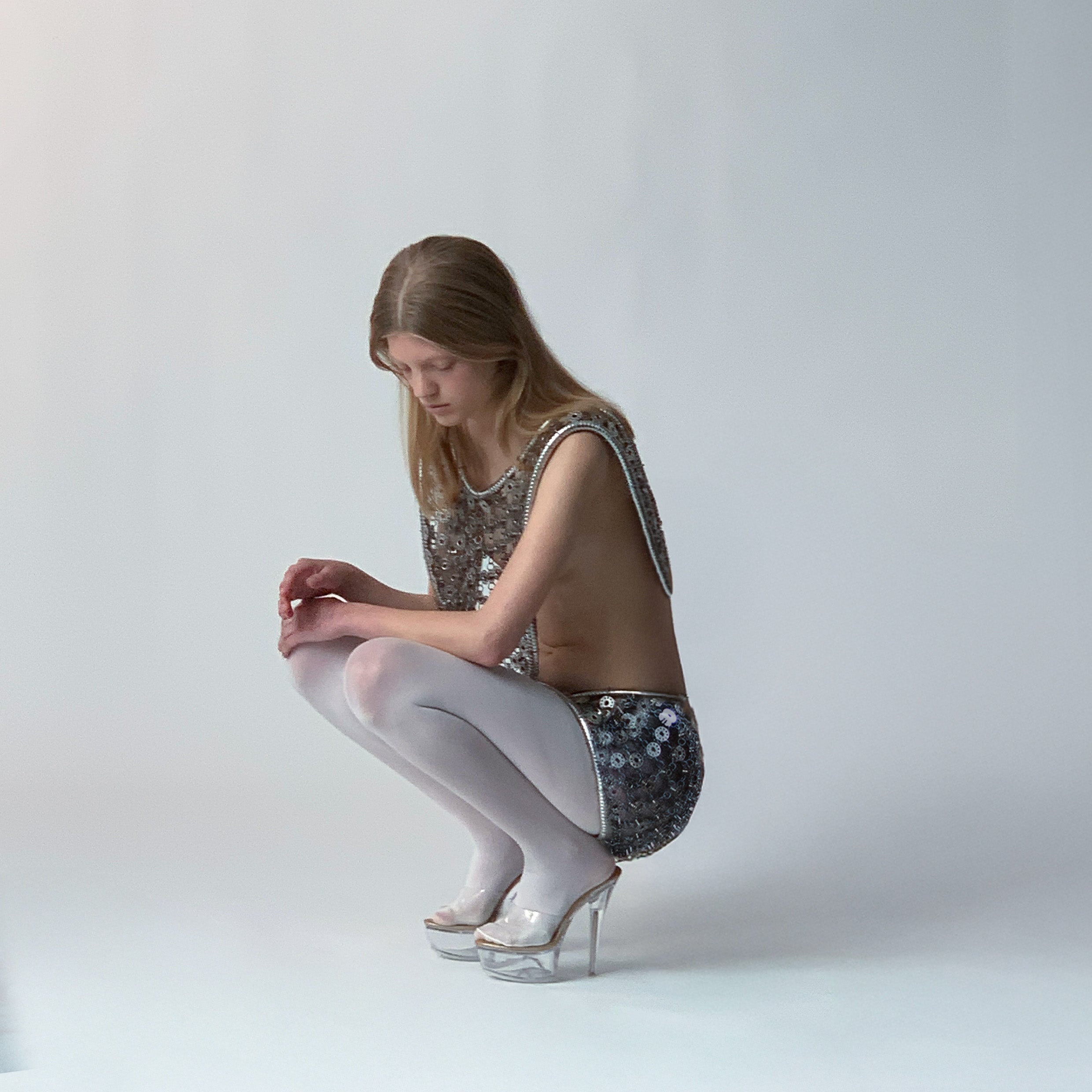 Person wearing a metallic bobbins-made outfit, featuring a mini skirt and a multi-wear top, on a light grey background 