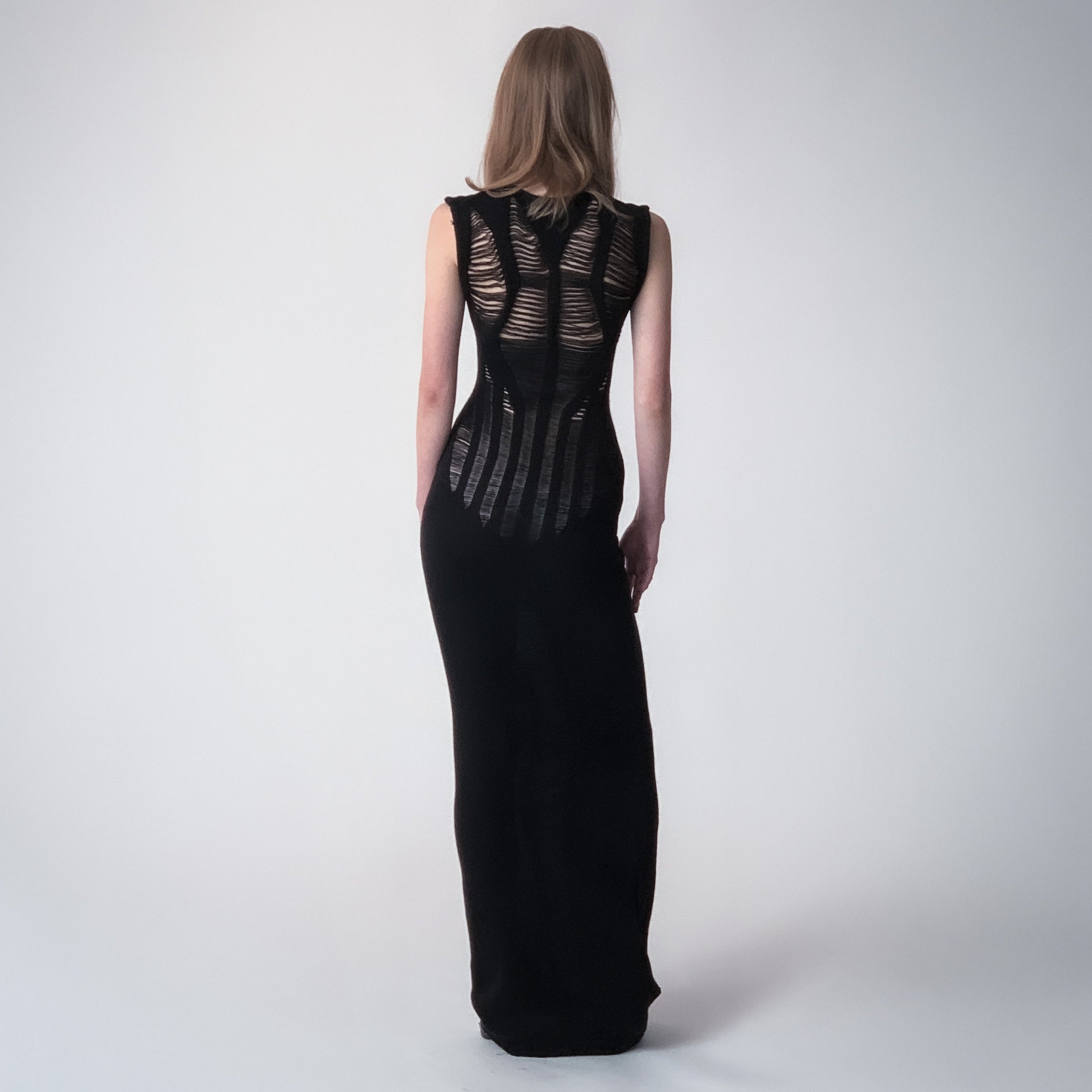 Long black knitted dress with floats details on a light grey background 