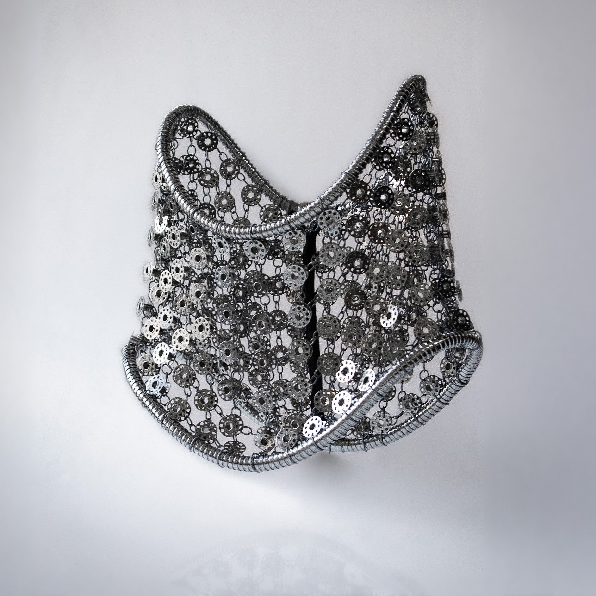 Metallic silver mini skirt out of bobbins on light gray background
