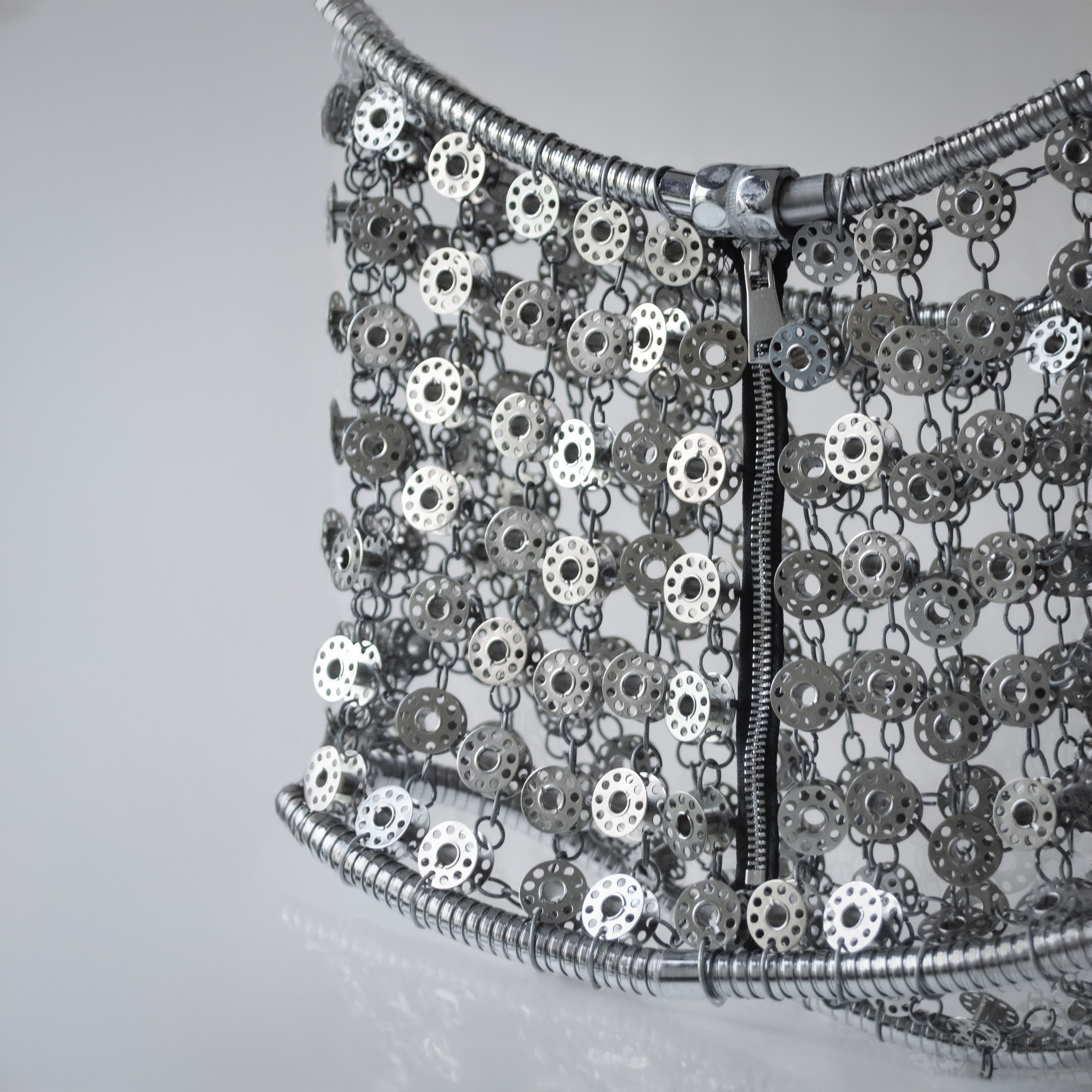 Metallic silver mini skirt out of bobbins on light gray background
