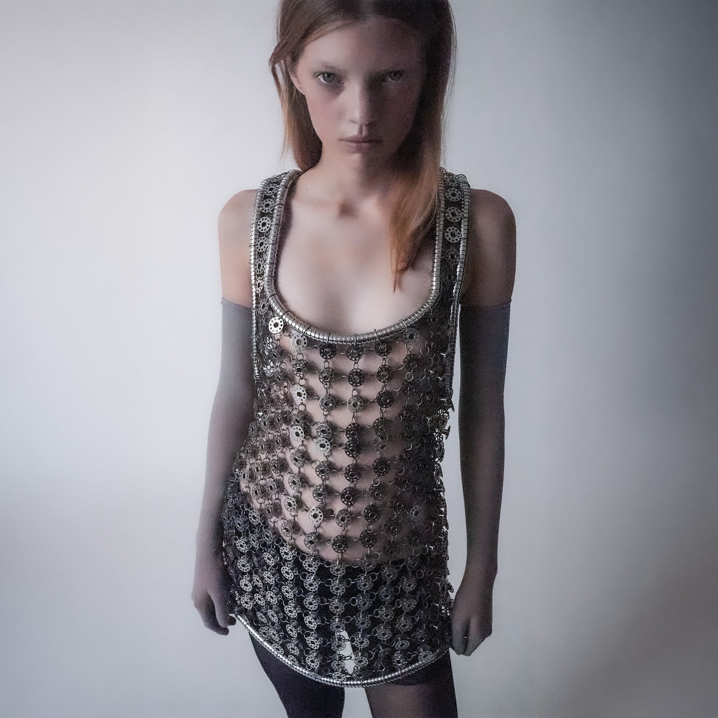 Person wearing a silver short dress out of bobbins on a light gray background 