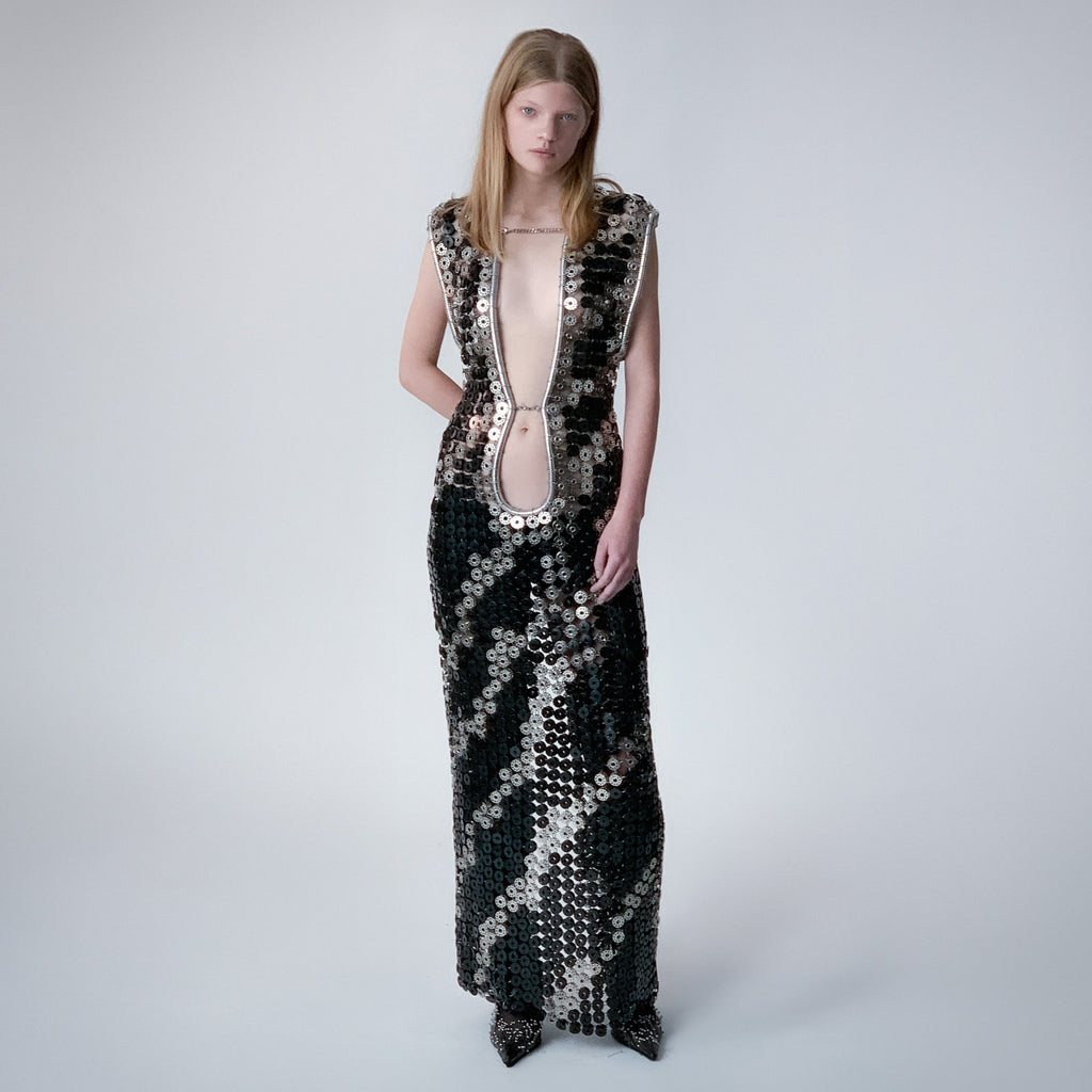 person wearing a long dress out of black and metallic  bobbins in a zebra pattern on a light gray background 